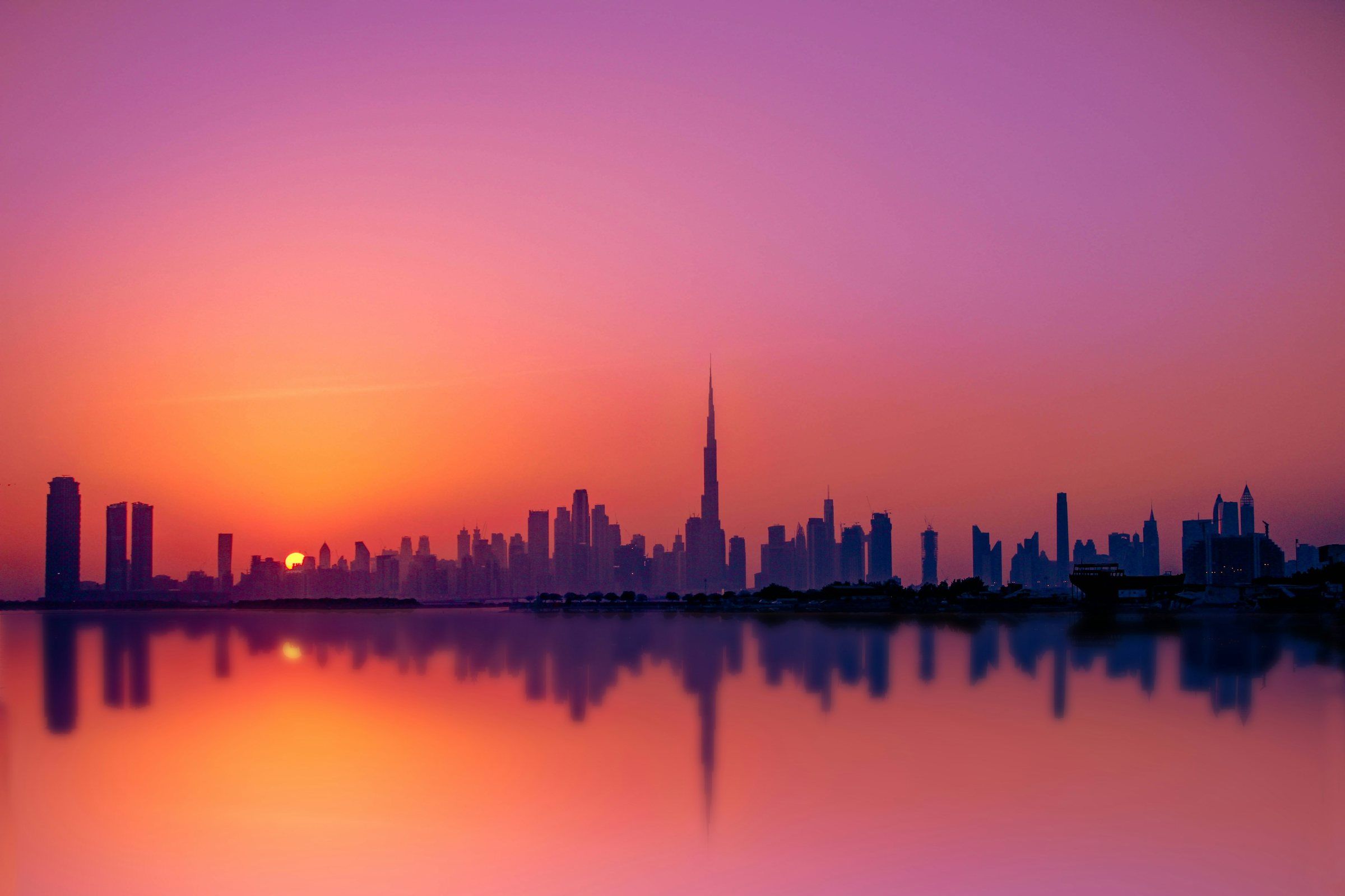 Скайлайн Дубая с Burj Khalifa на розовом закате, отражение в воде